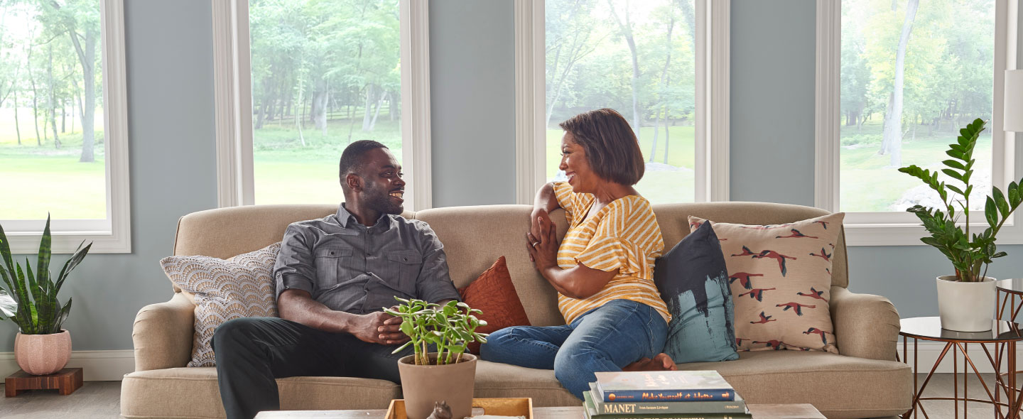An elderly man and woman sitting together on a sofa, enjoying each other's company and relaxing