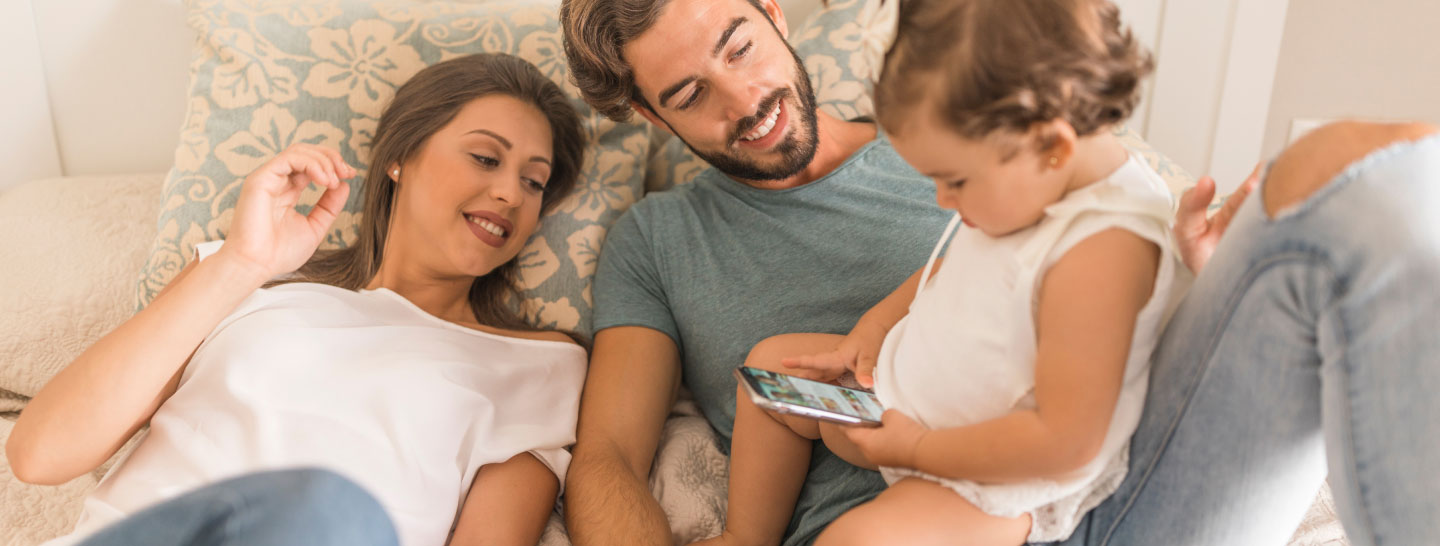 Man, woman, and children lying together on a bed, relaxing and enjoying family time.