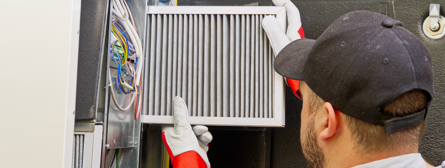 HVAC service technician changing dirty air filter in the central ventilation system