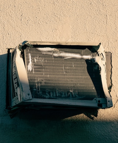 Old broken air conditioner on urban wall